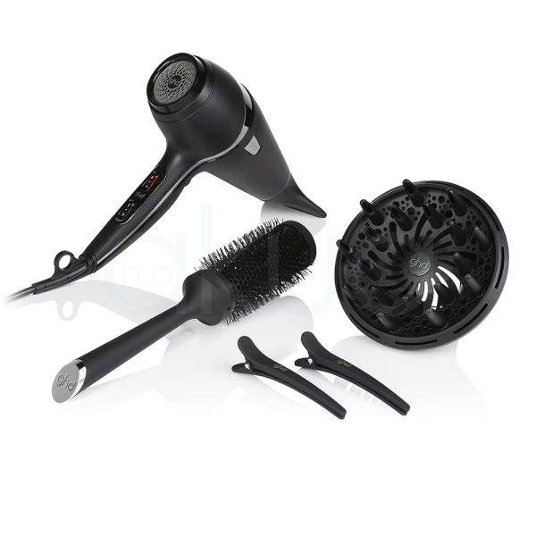 Secador de viaje air kit ghd el color predominante en la imagen es negro. Todos los objetos —el secador de pelo, el cepillo redondo, el difusor y las pinzas— son de color negro mate con algunos detalles metálicos en plateado, como el extremo del cepillo y pequeños acentos en el secador H2o Akua