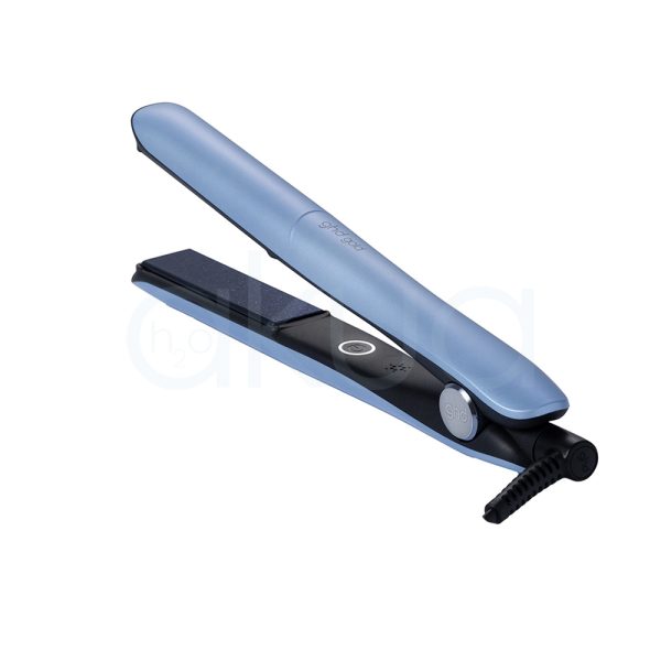 Plancha ghd Gold Blue Ice Collection de color azul claro en la parte exterior de su cuerpo, con un acabado mate. El interior, incluyendo las placas alisadoras y la base, es de color negro. Además, presenta detalles en gris en los botones y en la zona cercana al cable. El logotipo de la marca está impreso en color gris claro sobre el cuerpo azul H2o Akua