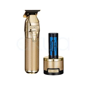 Maquina FXONE Gold Trimmer Babyliss Pro El color predominante es dorado metálico, presente tanto en el cuerpo principal de la máquina de corte como en la base del cargador y el mango del dispositivo. El recortador y la base tienen una textura grabada en dorado, lo que aporta un acabado elegante y lujoso. El cartucho de batería muestra detalles en azul translúcido con inscripciones en negro, añadiendo un contraste moderno al conjunto. Hay pequeños detalles en negro en la parte superior de la cuchilla y en la base del cargador, así como inscripciones en negro y azul en la batería H2o Akua