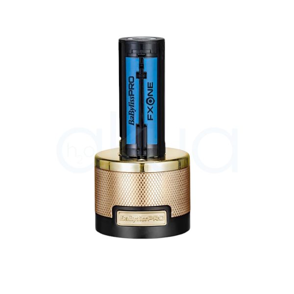 Maquina FXONE Gold Trimmer Babyliss Pro El color predominante es dorado metálico, presente tanto en el cuerpo principal de la máquina de corte como en la base del cargador y el mango del dispositivo. El recortador y la base tienen una textura grabada en dorado, lo que aporta un acabado elegante y lujoso. El cartucho de batería muestra detalles en azul translúcido con inscripciones en negro, añadiendo un contraste moderno al conjunto. Hay pequeños detalles en negro en la parte superior de la cuchilla y en la base del cargador, así como inscripciones en negro y azul en la batería H2o Akua