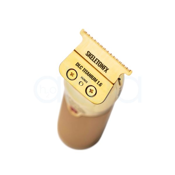 Maquina FXONE Gold Trimmer Babyliss Pro El color predominante es dorado metálico, presente tanto en el cuerpo principal de la máquina de corte como en la base del cargador y el mango del dispositivo. El recortador y la base tienen una textura grabada en dorado, lo que aporta un acabado elegante y lujoso. El cartucho de batería muestra detalles en azul translúcido con inscripciones en negro, añadiendo un contraste moderno al conjunto. Hay pequeños detalles en negro en la parte superior de la cuchilla y en la base del cargador, así como inscripciones en negro y azul en la batería H2o Akua