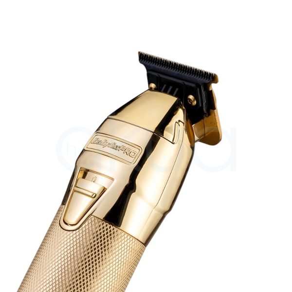 Maquina FXONE Gold Trimmer Babyliss Pro El color predominante es dorado metálico, presente tanto en el cuerpo principal de la máquina de corte como en la base del cargador y el mango del dispositivo. El recortador y la base tienen una textura grabada en dorado, lo que aporta un acabado elegante y lujoso. El cartucho de batería muestra detalles en azul translúcido con inscripciones en negro, añadiendo un contraste moderno al conjunto. Hay pequeños detalles en negro en la parte superior de la cuchilla y en la base del cargador, así como inscripciones en negro y azul en la batería H2o Akua