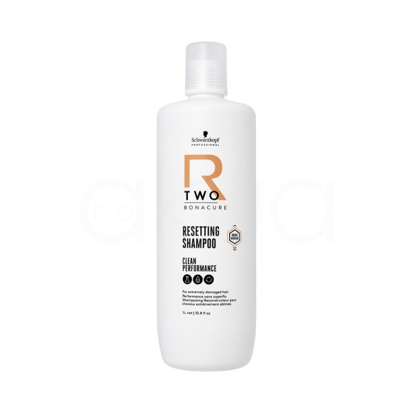 Champu Bonacure R-TWO Restaurador 1000ml El color predominante del envase es blanco. Los textos y elementos gráficos incluyen detalles en negro (para la información), un logotipo en negro y un elemento decorativo llamativo en naranja (letra "R" y algunos detalles geométricos). La tapa del envase también es de color blanco translúcido y mate. H2o Akua