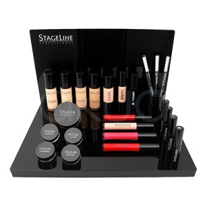 Expositor Stageline 09526_1. Expositor de maquillaje rectangular, de base y fondo planos y color negro brillante. Sobre este expositor se distribuyen simétricamente varios cosméticos de la marca Stageline Professional, en envases cilíndricos, tubulares o en tarritos redondos, predominando los colores negro, beige y algunos tonos de rojo y rosa en los productos. H2o Akua