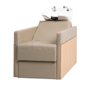 Lavacabezas Rustik Beige H2oAkua. La imagen muestra un lavacabezas de peluquería moderno, compuesto por un sillón tapizado en color beige con apoyabrazos anchos y estructura lateral de aspecto madera. En la parte superior, integrado al respaldo, se encuentra una cubeta o pila de lavado de cerámica blanca diseñada para lavar el cabello de los clientes.