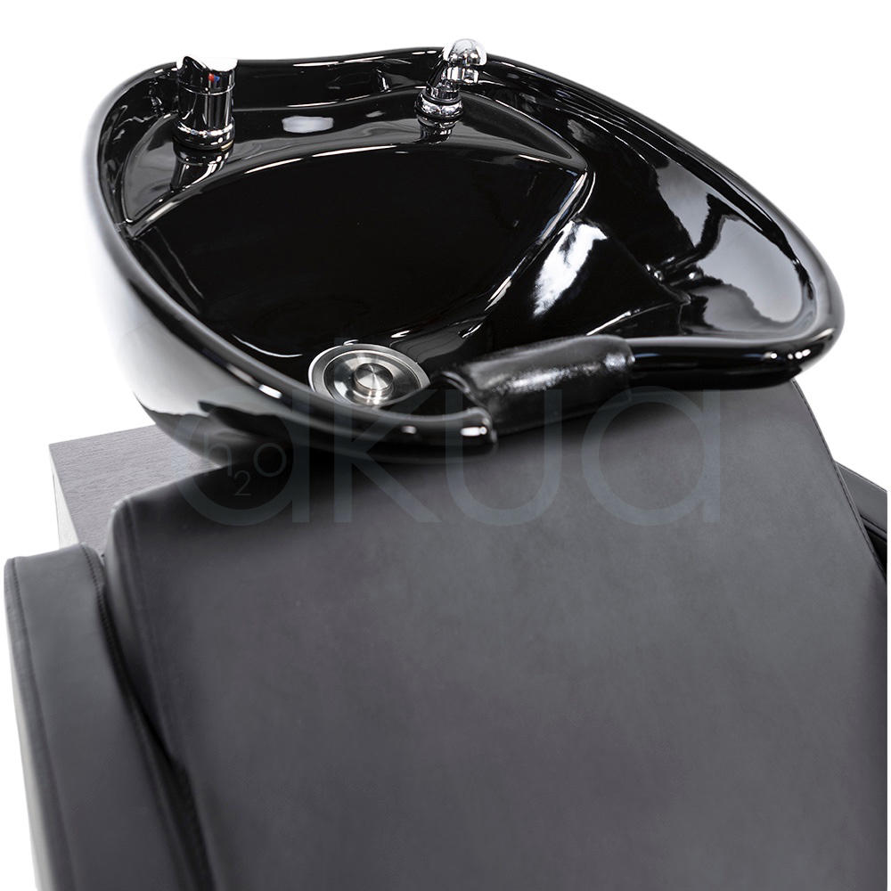 Lavacabezas Rustik negro H2oAkua. La imagen muestra un lavacabezas de peluquería moderno, compuesto por un sillón tapizado en color negro con apoyabrazos anchos y estructura lateral de aspecto madera. En la parte superior, integrado al respaldo, se encuentra una cubeta o pila de lavado de cerámica negra diseñada para lavar el cabello de los clientes.