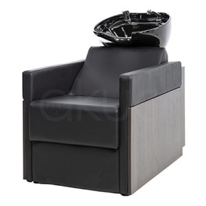 Lavacabezas Rustik negro H2oAkua. La imagen muestra un lavacabezas de peluquería moderno, compuesto por un sillón tapizado en color negro con apoyabrazos anchos y estructura lateral de aspecto madera. En la parte superior, integrado al respaldo, se encuentra una cubeta o pila de lavado de cerámica negra diseñada para lavar el cabello de los clientes.