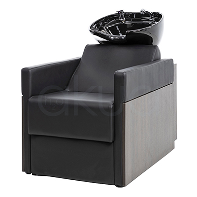 Lavacabezas Rustik negro H2oAkua. La imagen muestra un lavacabezas de peluquería moderno, compuesto por un sillón tapizado en color negro con apoyabrazos anchos y estructura lateral de aspecto madera. En la parte superior, integrado al respaldo, se encuentra una cubeta o pila de lavado de cerámica negra diseñada para lavar el cabello de los clientes.