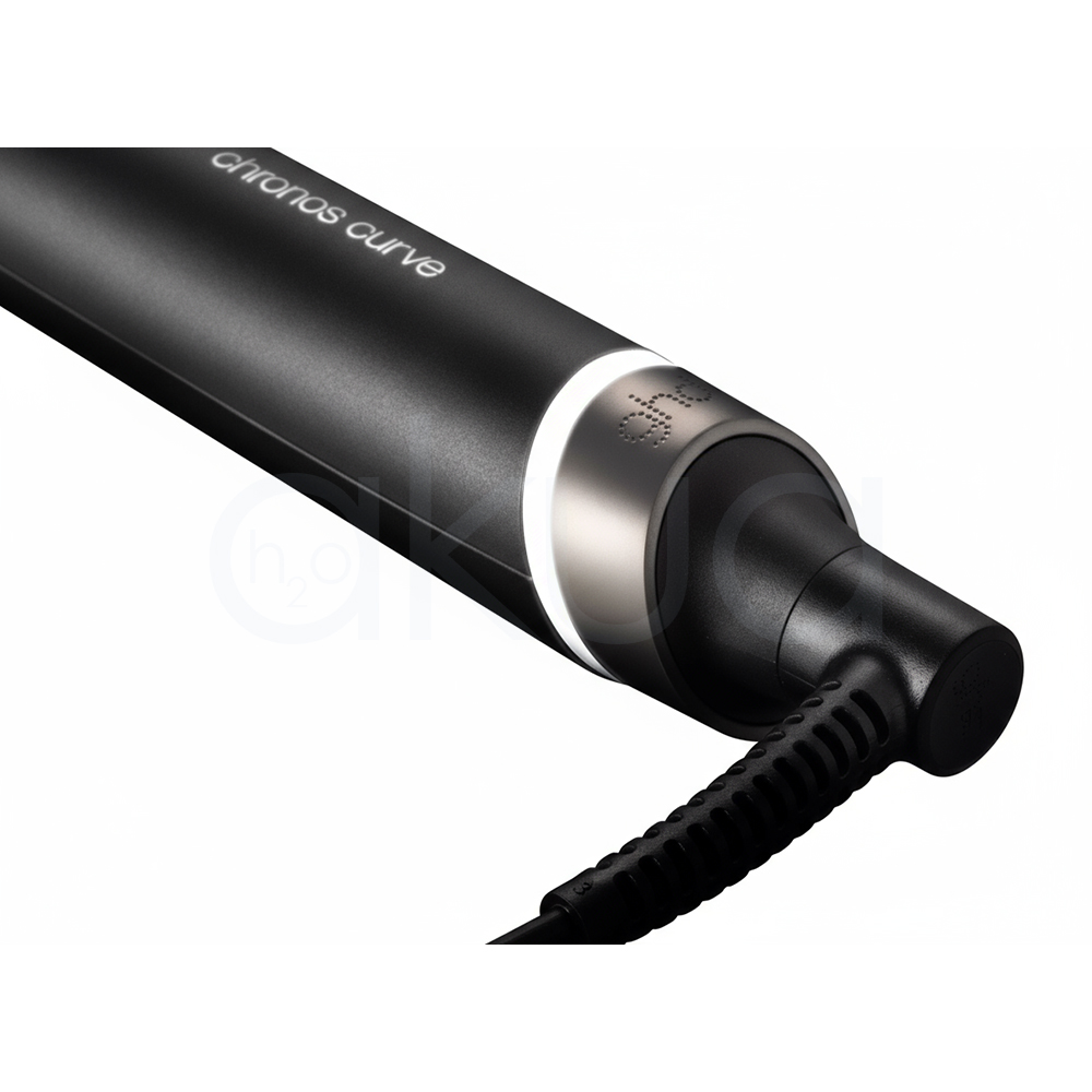 Rizador ghd Chronos Curve Max. La imagen muestra el rizador de pelo profesional ghd Chronos Curve Max junto a su caja de presentación. Ambos elementos están sobre un fondo completamente blanco que resalta el diseño elegante y moderno del producto. El rizador es de color negro con detalles metálicos y se distingue por su forma cónica, ideal para crear ondas y rizos definidos en el cabello. La caja negra presenta el nombre del producto y el logotipo de la marca ghd en letras blancas, mostrando una estética minimalista y premium. H2o Akua