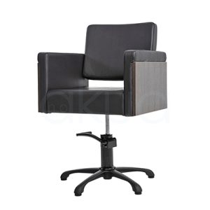 Sillon Rustik Negro H2oAkua. La imagen muestra una silla de peluquería profesional de diseño moderno y minimalista. Tiene estructura cuadrada, tapizada en polipiel color negro, con apoyabrazos rectos que combinan el mismo tapizado y paneles laterales en acabado madera clara. El respaldo es también tapizado y presenta una ligera inclinación para mayor comodidad. La base es metálica, cromada y en forma de estrella con cinco patas, dotada de un sistema hidráulico ajustable en altura.