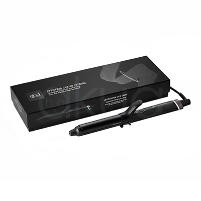 Tenacilla ghd Chronos Curve Classic. La imagen muestra la tenacilla de pelo profesional ghd Chronos Curve Classic junto a su caja de presentación. Ambos elementos están sobre un fondo completamente blanco que resalta el diseño elegante y moderno del producto. La tenacilla es de color negro con detalles metálicos y se distingue por su forma cónica, ideal para crear ondas y rizos definidos en el cabello. La caja negra presenta el nombre del producto y el logotipo de la marca ghd en letras blancas, mostrando una estética minimalista y premium. H2o Akua