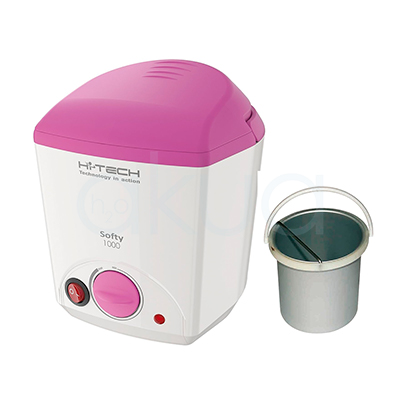 Fundidor cera Softy 1000ml. En la imagen se ve un fundidor de parafina o cera de diseño compacto, de forma rectangular con bordes redondeados, en color blanco con tapa rosa. En el frontal lleva un gran mando giratorio también rosa para regular la temperatura, un interruptor de encendido rojo y un piloto luminoso; junto al aparato aparece un cubo metálico extraíble con asa, destinado a contener la cera o parafina durante el calentamiento. H2o Akua