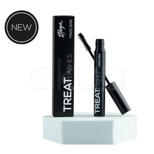 Mascara de pestañas Treat Lashes Thuya. La imagen muestra un producto de cosmética: una máscara de pestañas negra de la marca Thuya, llamada “Treat Lashes”. Se ve la caja del producto de pie, con el nombre “TREAT LASHES” en vertical. A la derecha aparece el tubo abierto con el cepillo aplicador extraído. En la parte superior izquierda hay un icono circular que dice “NEW”. H2o Akua