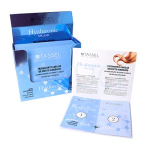 Tratamiento Capilar para Hidratación Profunda Tassel 07438. Caja abierta de tratamiento capilar “Hyaluronic Splash” de la marca Tassel en color azul degradado. A la derecha se muestran dos sobres numerados (1 y 2) junto a un folleto informativo con instrucciones. El producto está orientado a hidratación y reparación del cabello con efecto inmediato. H2o Akua