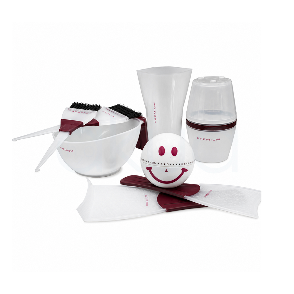 Kit tecnico premium tintura H2oAkua. El conjunto incluye un bol mezclador blanco con dos brochas aplicadoras apoyadas encima, ambas con mango en color burdeos y cerdas negras. En la parte trasera aparece un vaso medidor translúcido y un recipiente dosificador con tapa semitransparente. En el centro destaca una pequeña esfera blanca decorada con una cara sonriente en color rosa oscuro. En la parte inferior se observan dos paletas protectoras translúcidas con detalles en burdeos. Todos los accesorios mantienen un diseño moderno y minimalista en tonos blancos y burdeos, orientado al uso profesional en peluquería y tintura capilar.”