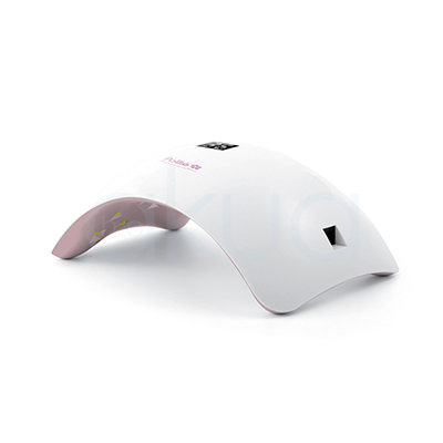 Lampara de uñas Led Moon Light. Lámpara LED profesional para uñas con diseño curvo y compacto en color blanco con detalles rosados. El dispositivo tiene forma arqueada para introducir cómodamente la mano o el pie durante el secado de esmaltes y geles semipermanentes. En la parte superior incorpora una pequeña pantalla digital y en el interior se observan luces LED destinadas al curado rápido y uniforme del producto. Su diseño moderno y minimalista está orientado a trabajos de manicura profesional y uso estético. H2o Akua