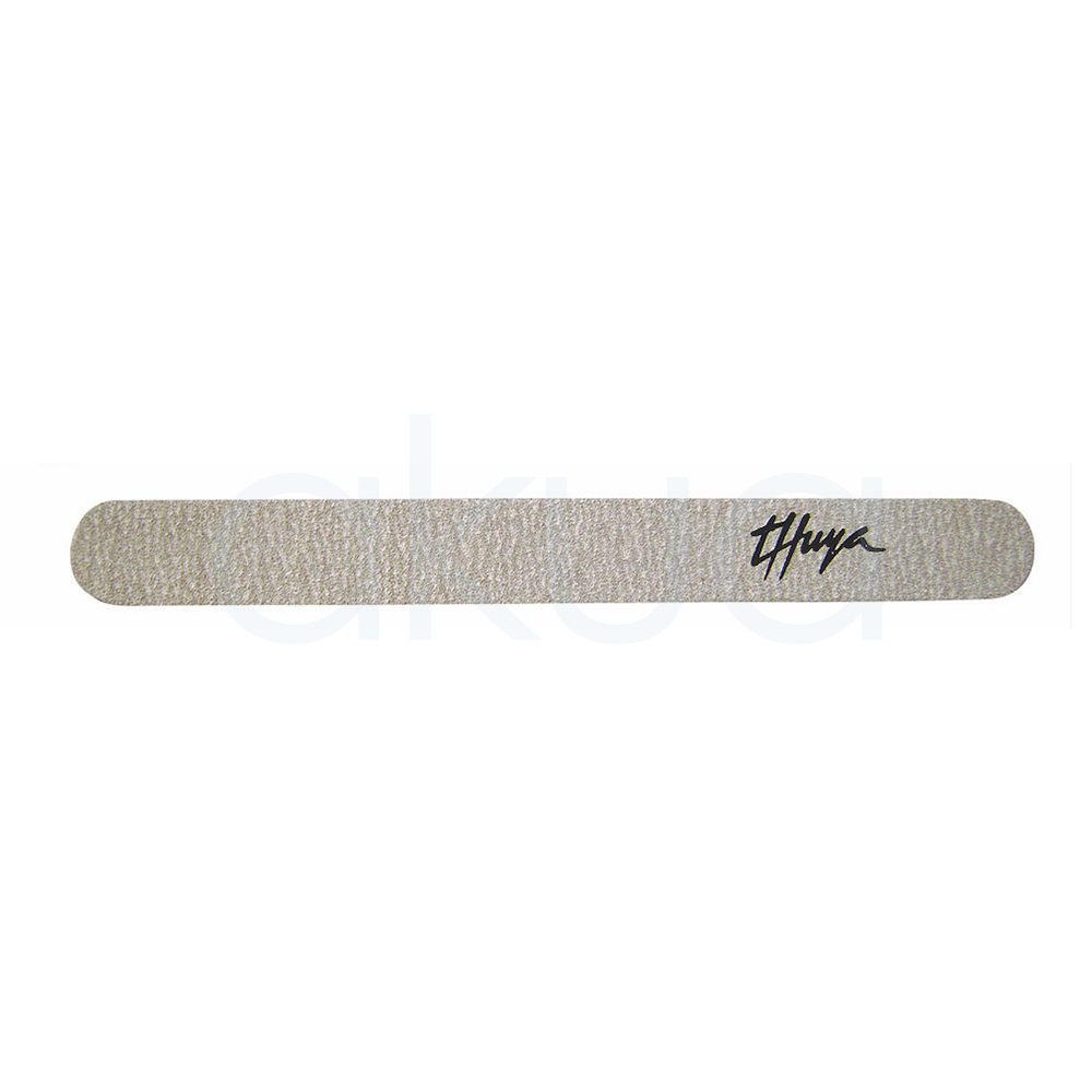 Lima acolchada gris 100/180 granulo grueso Thuya. De diseño alargado y bordes redondeados. La lima presenta una superficie gris texturizada de grano abrasivo, ideal para trabajos de manicura y limado de uñas artificiales o naturales. En uno de los extremos aparece el logotipo negro de Thuya. El producto destaca por su acabado profesional y su formato cómodo para uso en estética y nail art. H2o Akua