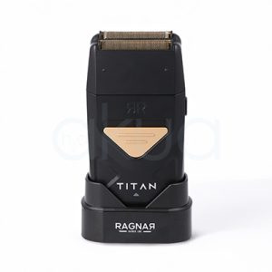 Afeitadora Titan Ragnar. Afeitadora profesional de acabado tipo foil en color negro mate con detalles metálicos dorados. En la parte superior incorpora un doble cabezal de láminas metálicas diseñado para proporcionar un afeitado preciso y apurado. El cuerpo presenta un diseño compacto y ergonómico con un panel triangular dorado en la zona frontal y la inscripción "TITAN" en letras blancas. La afeitadora está colocada sobre una base de carga negra con el logotipo "Ragnar Barber Line" visible en la parte frontal. La imagen se presenta sobre un fondo claro, resaltando el aspecto moderno, elegante y profesional de la herramienta, especialmente orientada a barberías y acabados de precisión. H2o Akua