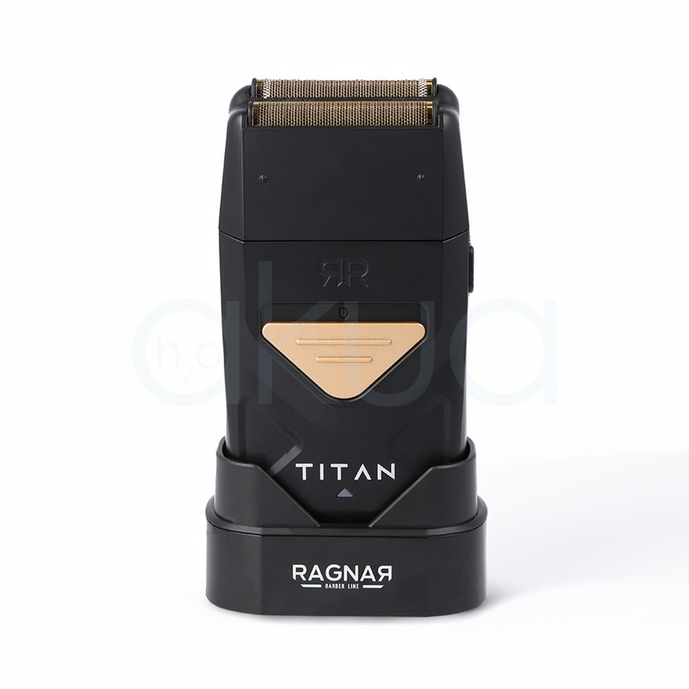 Afeitadora Titan Ragnar. Afeitadora profesional de acabado tipo foil en color negro mate con detalles metálicos dorados. En la parte superior incorpora un doble cabezal de láminas metálicas diseñado para proporcionar un afeitado preciso y apurado. El cuerpo presenta un diseño compacto y ergonómico con un panel triangular dorado en la zona frontal y la inscripción "TITAN" en letras blancas. La afeitadora está colocada sobre una base de carga negra con el logotipo "Ragnar Barber Line" visible en la parte frontal. La imagen se presenta sobre un fondo claro, resaltando el aspecto moderno, elegante y profesional de la herramienta, especialmente orientada a barberías y acabados de precisión. H2o Akua