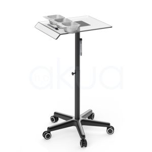 Carrito auxiliar Velura H2oAkua. Carrito auxiliar profesional de peluquería con estructura metálica negra y bandeja superior transparente. La bandeja incorpora tres recipientes para mezcla de tintes o tratamientos capilares, un soporte lateral para documentos o tabletas y un espacio destinado a herramientas de trabajo. Cuenta con columna central regulable en altura mediante pomo de ajuste y una base de cinco brazos con ruedas giratorias que facilitan su movilidad. Su diseño moderno y funcional está pensado para optimizar la organización de productos y accesorios durante servicios de coloración, tratamientos capilares y trabajos técnicos en peluquería.