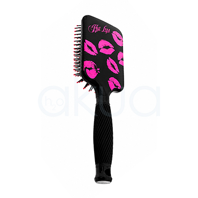 Cepillo desentedante Kisses Giubra. Cepillo paddle desenredante de color negro con diseño decorativo de labios en tonos rosa fucsia impresos sobre la parte trasera del cabezal. En la esquina superior izquierda aparece la frase "Hot Lips" escrita en letra cursiva rosa. El cepillo cuenta con púas negras flexibles terminadas en pequeñas bolitas rosas para un cepillado suave del cuero cabelludo. Su mango ergonómico negro presenta un acabado estriado que mejora el agarre y un orificio en el extremo para colgarlo. La imagen está tomada sobre un fondo claro, destacando el contraste entre el negro brillante del cepillo y los detalles decorativos en color rosa. H2o akua