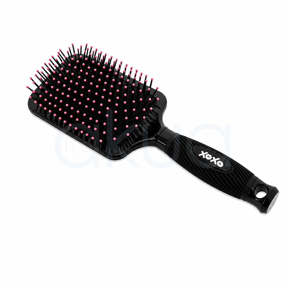 Cepillo desentedante Kisses Giubra. Cepillo paddle desenredante de color negro con diseño decorativo de labios en tonos rosa fucsia impresos sobre la parte trasera del cabezal. En la esquina superior izquierda aparece la frase "Hot Lips" escrita en letra cursiva rosa. El cepillo cuenta con púas negras flexibles terminadas en pequeñas bolitas rosas para un cepillado suave del cuero cabelludo. Su mango ergonómico negro presenta un acabado estriado que mejora el agarre y un orificio en el extremo para colgarlo. La imagen está tomada sobre un fondo claro, destacando el contraste entre el negro brillante del cepillo y los detalles decorativos en color rosa. H2o akua