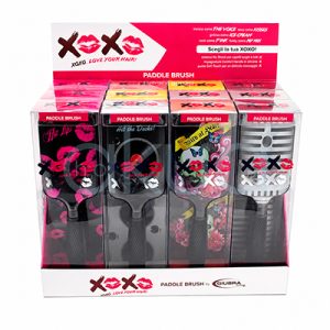 Expositor 12 cepillos desenredantes Giubra Expositor de sobremesa para cepillos paddle de la colección XOXO by Giubra. El expositor, de color blanco y rosa, contiene varios cepillos presentados en cajas transparentes individuales. Cada cepillo muestra un diseño diferente y llamativo, incluyendo estampados de labios rosas, un tocadiscos de vinilo, ilustraciones artísticas con calaveras y mariposas, y patrones geométricos en tonos grises. En la parte superior destaca un panel promocional con el logotipo XOXO formado por letras y besos en color rosa, acompañado del lema “Love Your Hair!”. El conjunto presenta una imagen moderna, juvenil y atractiva, diseñada para captar la atención en salones de peluquería y puntos de venta de productos de belleza. H2o Akua