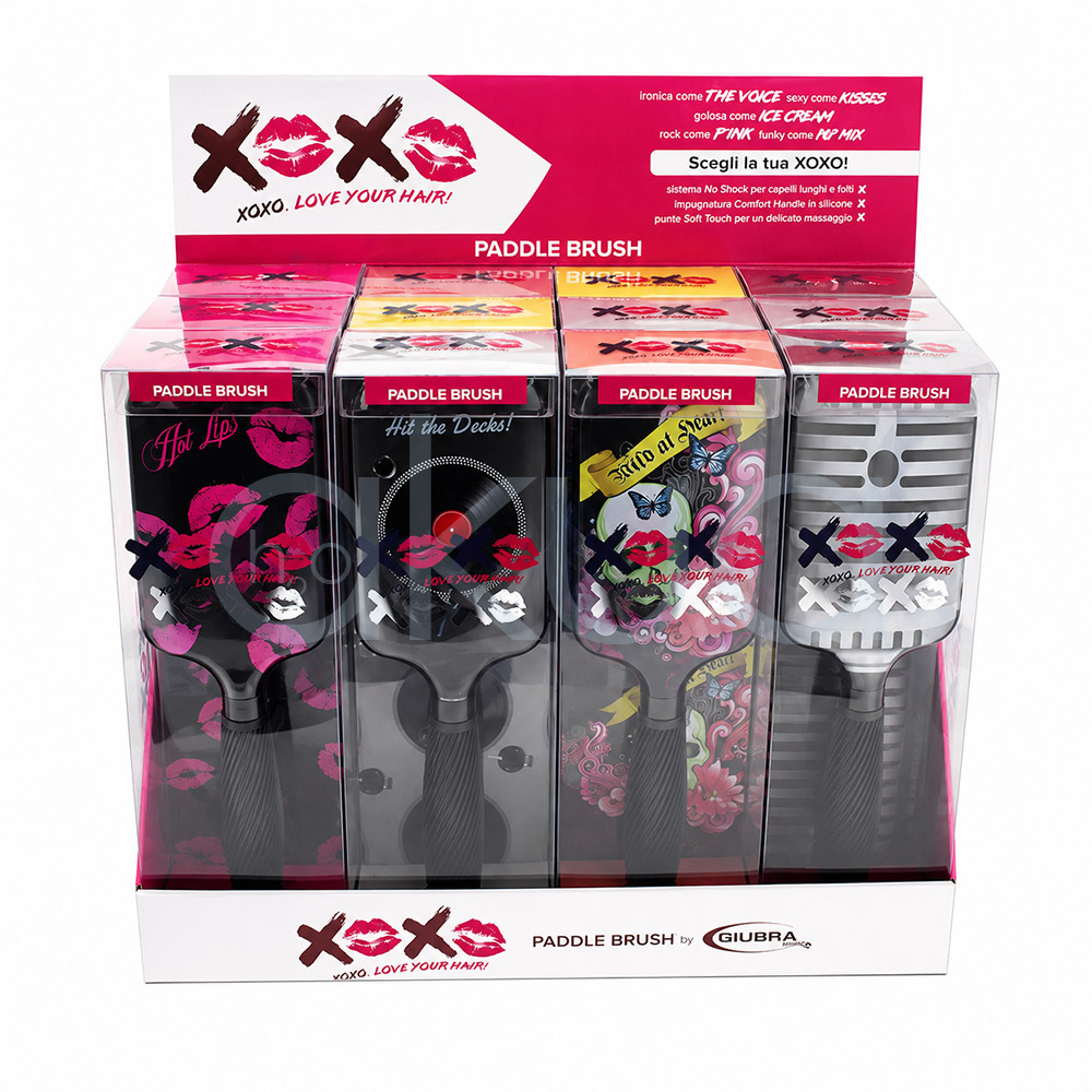 Expositor 12 cepillos desenredantes Giubra Expositor de sobremesa para cepillos paddle de la colección XOXO by Giubra. El expositor, de color blanco y rosa, contiene varios cepillos presentados en cajas transparentes individuales. Cada cepillo muestra un diseño diferente y llamativo, incluyendo estampados de labios rosas, un tocadiscos de vinilo, ilustraciones artísticas con calaveras y mariposas, y patrones geométricos en tonos grises. En la parte superior destaca un panel promocional con el logotipo XOXO formado por letras y besos en color rosa, acompañado del lema “Love Your Hair!”. El conjunto presenta una imagen moderna, juvenil y atractiva, diseñada para captar la atención en salones de peluquería y puntos de venta de productos de belleza. H2o Akua