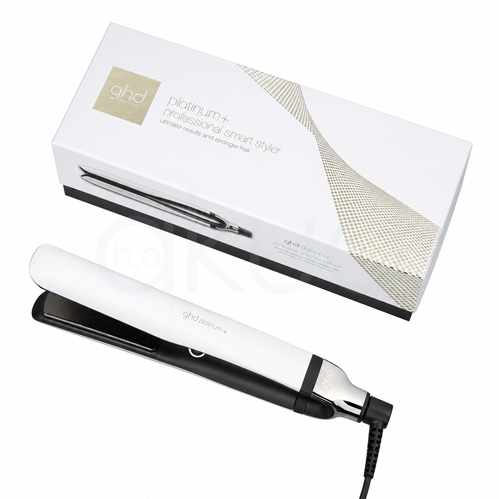 Plancha ghd Platinum+ blanca. Plancha de pelo GHD Platinum+ en color blanco con detalles negros y metálicos, colocada sobre un fondo blanco junto a su caja original a juego. La plancha aparece cerrada en posición diagonal, destacando su diseño elegante y minimalista. La caja blanca incorpora detalles dorados y la imagen del producto en uno de sus laterales, transmitiendo una estética moderna y profesional orientada al cuidado y peinado del cabello. H2o Akua